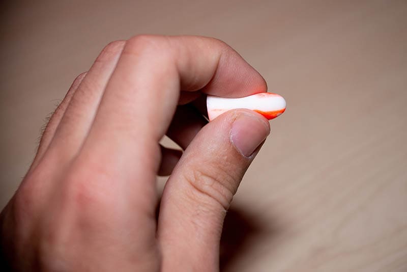 Unrecognizable hand holding color ear plug orange