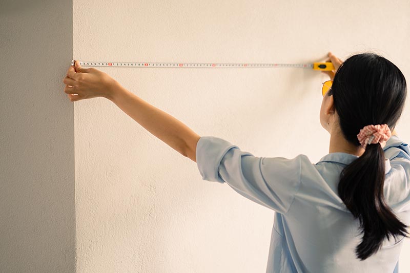 Woman measuring the size of the wall