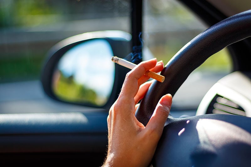 Woman smoking a cigarette at the wheel of a car