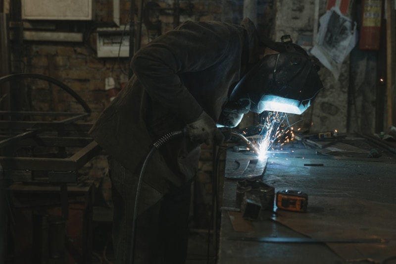 Worker using a plasma cutter on steel plate