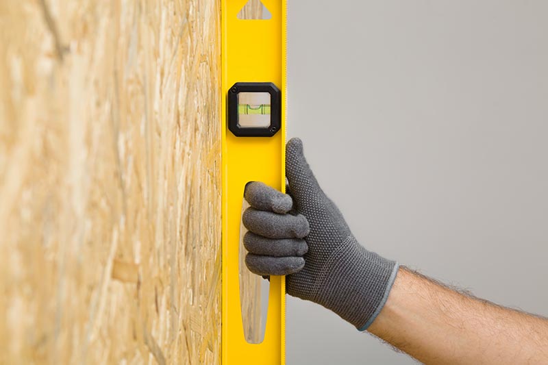 Young adult man hands using yellow spirit level