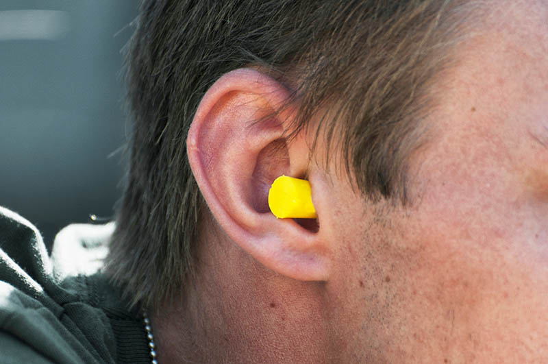 a male person with a yellow earplug in his ear