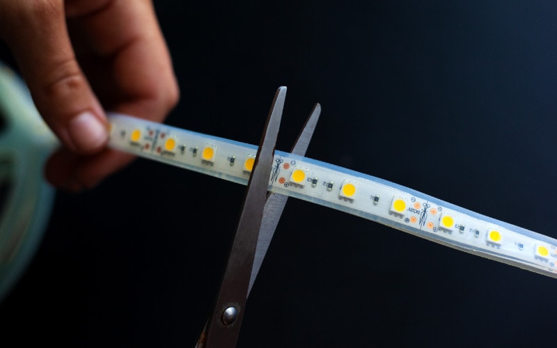 a person cutting a LED strip light with scissors