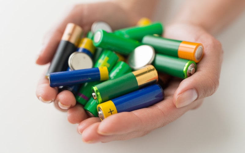 a person's hands holding different kinds of batteries