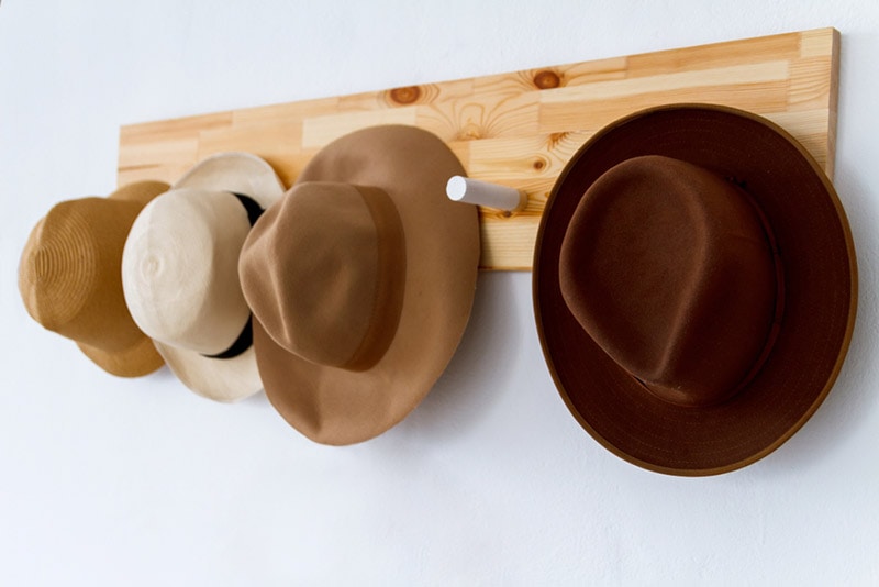 a set of hats hanging on a wooden hanger