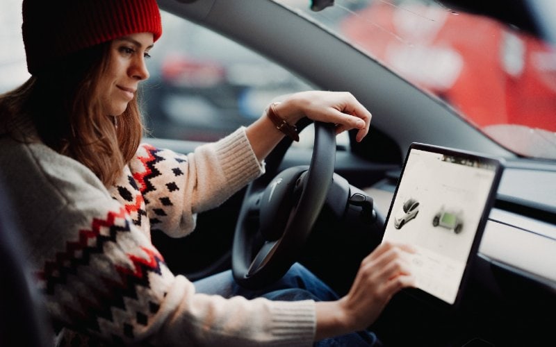 a woman operating a Tesla Model 3 sedan car