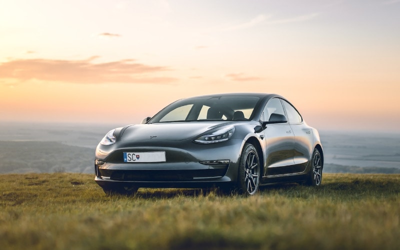 black Tesla sedan car parked on grass