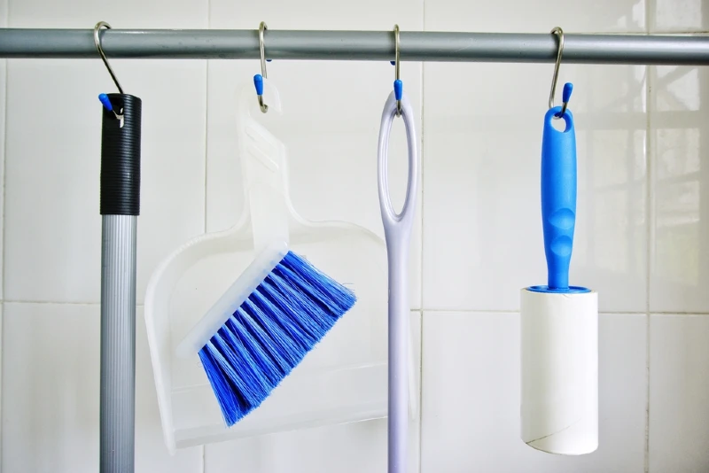 cleaning supplies hanging from s-hooks on a rod