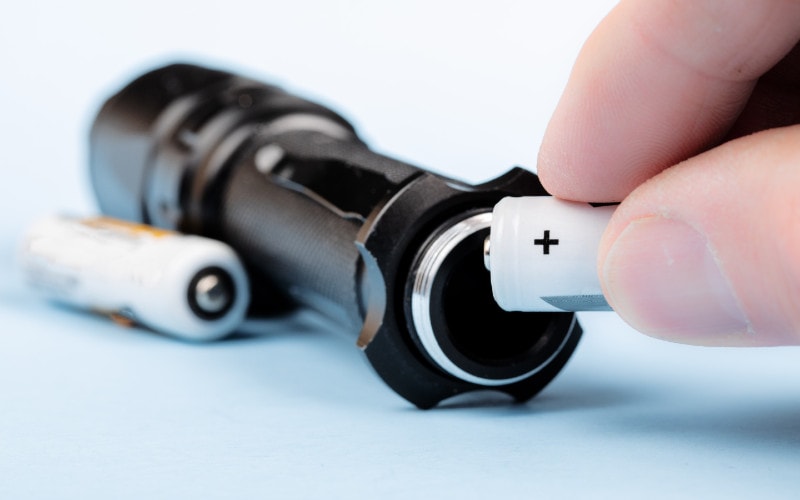 close up of a person putting batteries into a flashlight