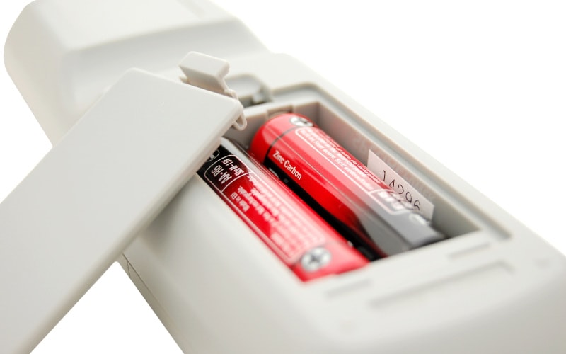 close up of a white remote control with zinc carbon batteries