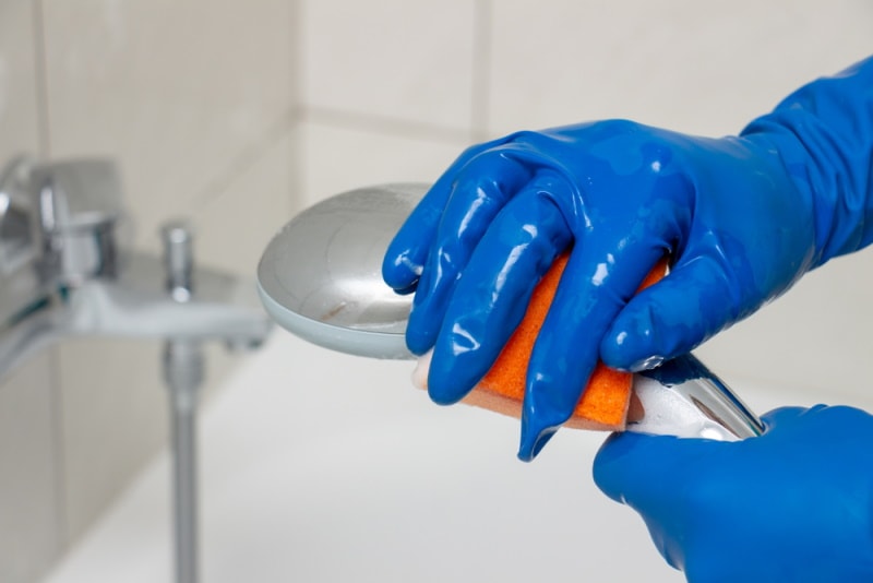 man cleaning shower head
