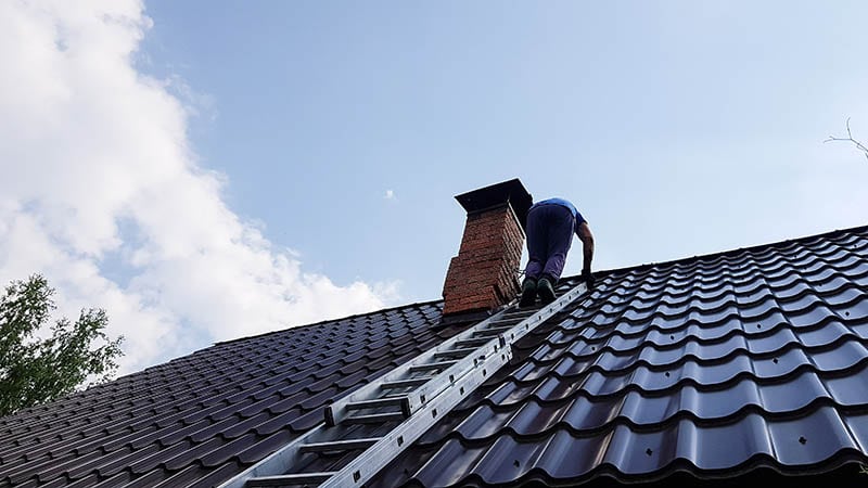 man climbing on a ladder on the sloped roof