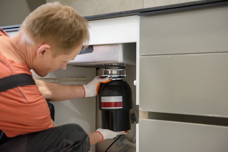 man removing the garbage disposal unit