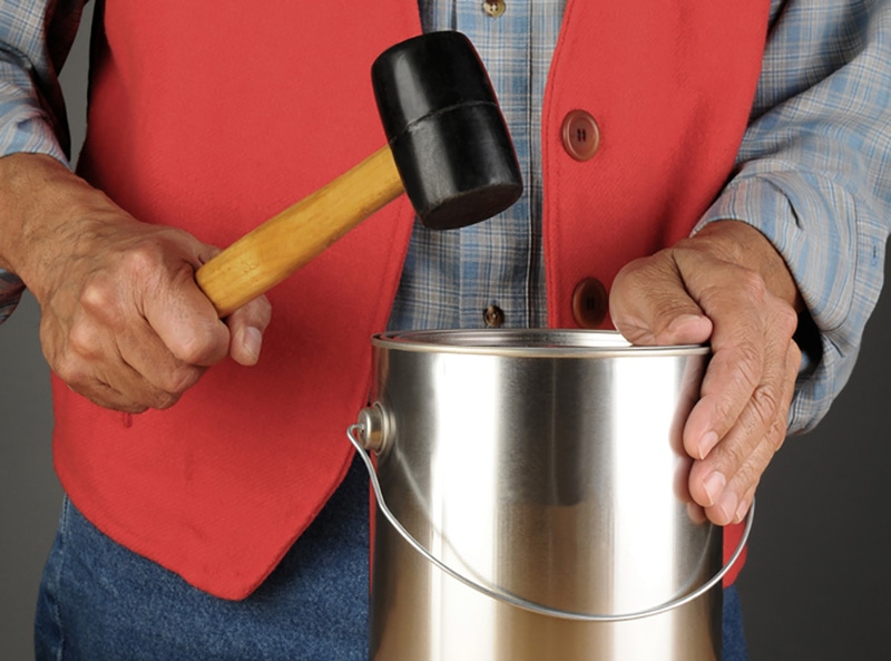 man sealing the paint can lid with rubber mallet