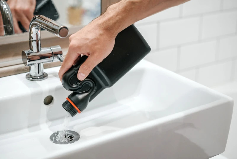 person pouring drain cleaner clog remover down the drain