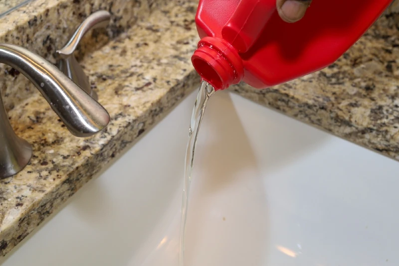 person pouring liquid drain cleaner down the sink