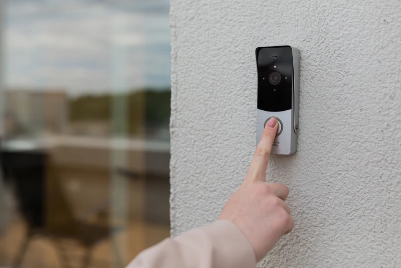 person pressing the button on a doorbell with camera