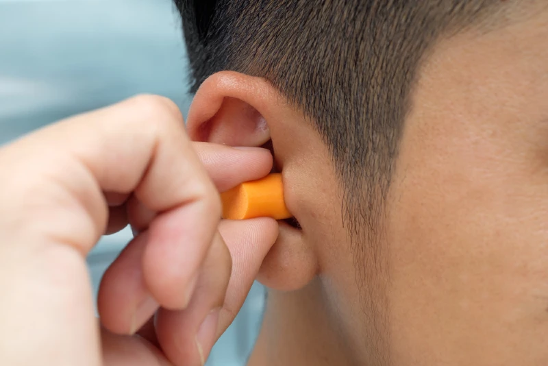 person putting protective earplug into their ear