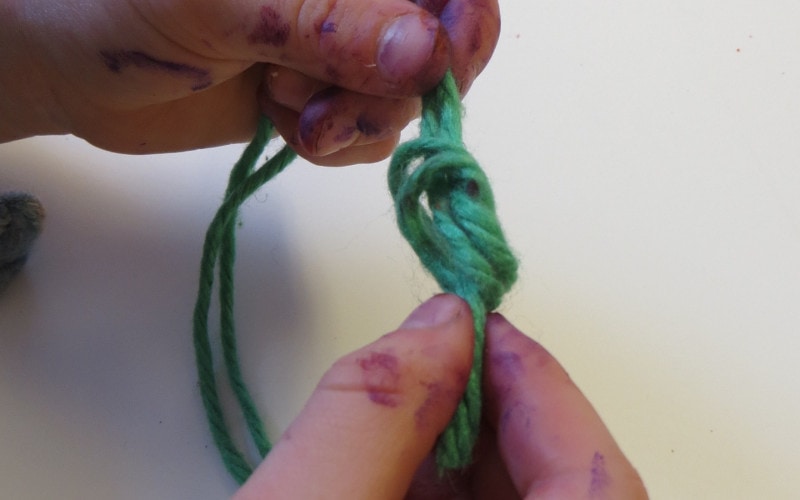 person tying the end of yarn to make a knot