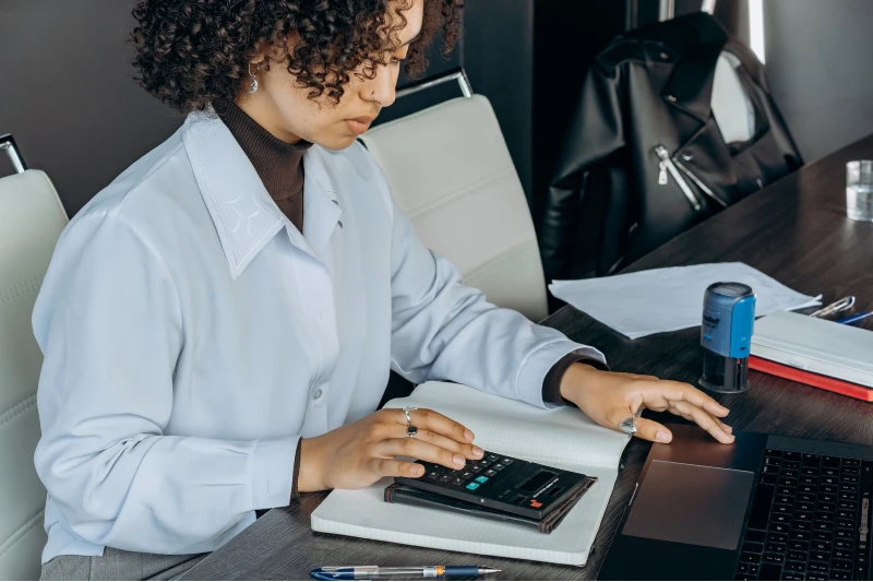 person using a calculator in front of laptop computer