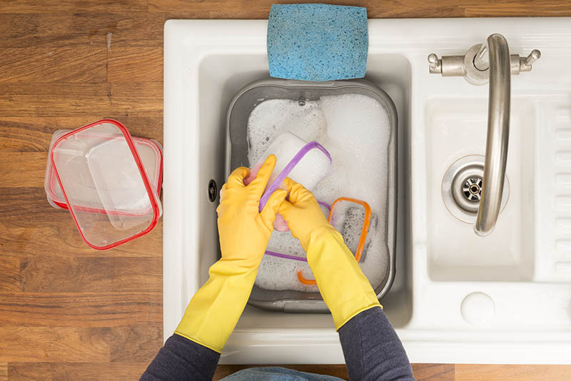 person washing containers on sink