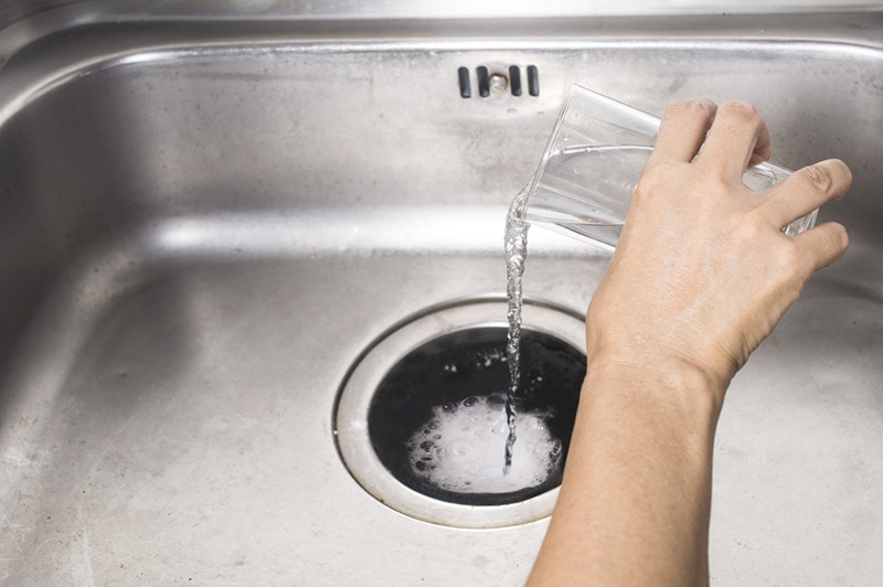 pouring baking soda and vinegar into the sink