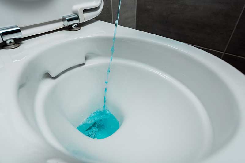 pouring blue liquid on toilet