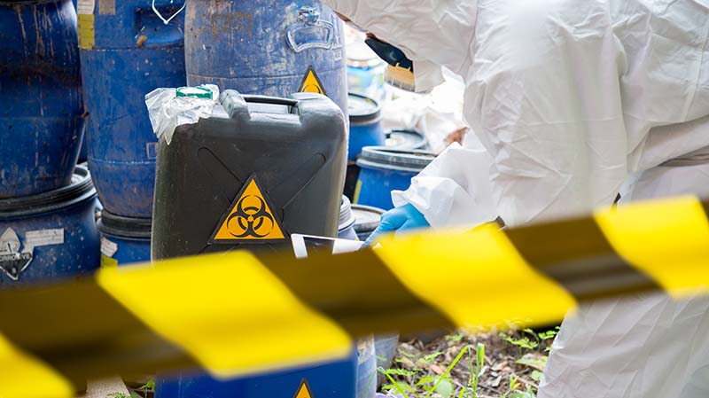 scientist wearing protective suit checking chemical waste
