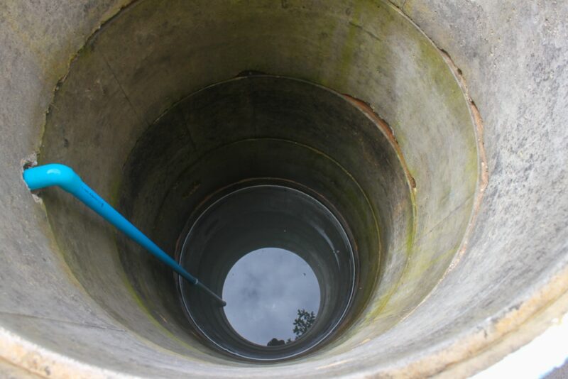 scooping water with buckets from water well
