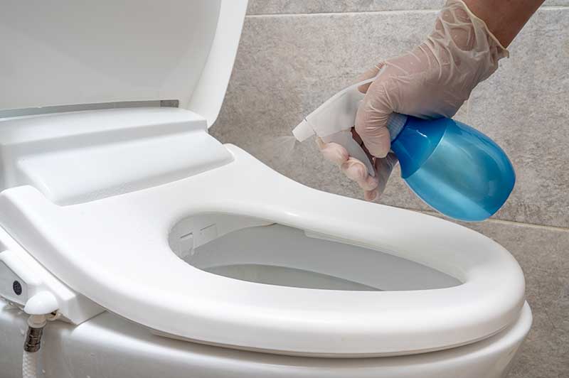spraying toilet with cleaning spray