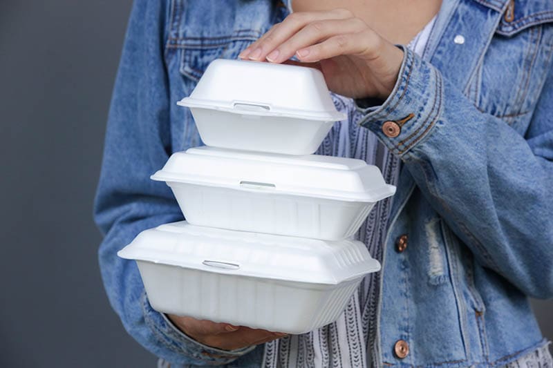woman carrying styrofoam food boxes