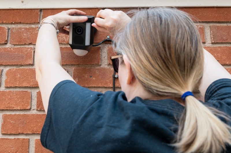 woman fixing floodlight camera