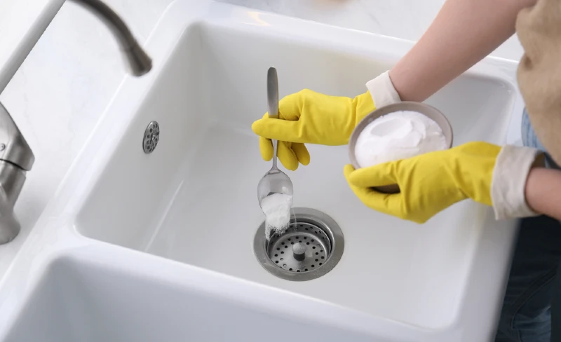 woman pouring powder drain cleaner down the drain