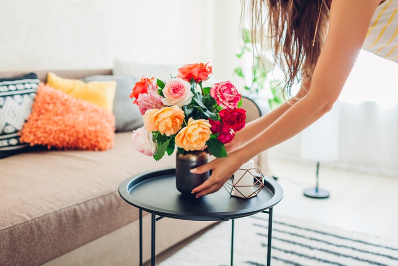 woman puts vase with flowers on the table