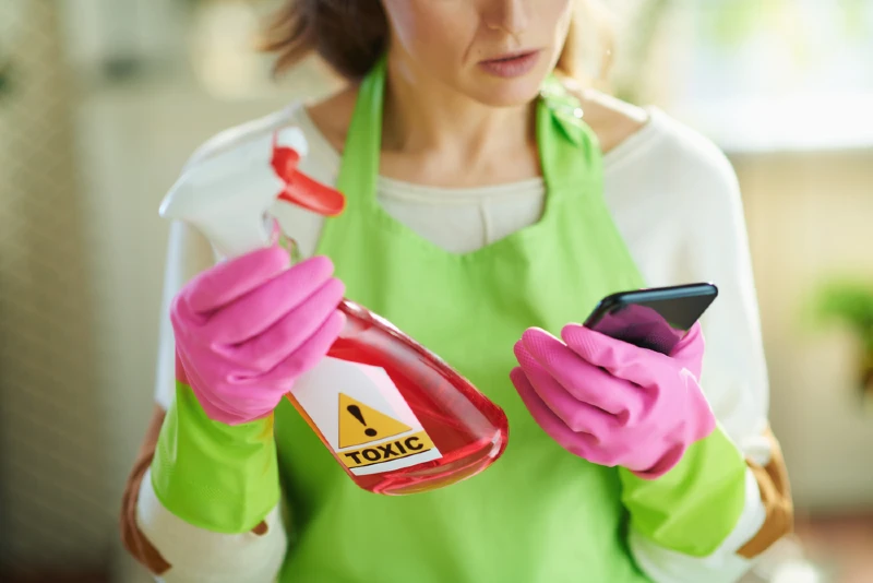 woman wearing apron and gloves holding up a toxic