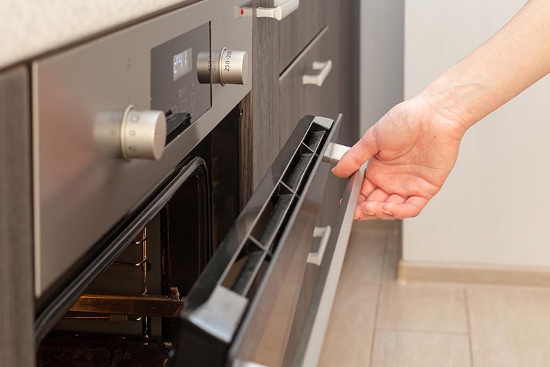 women hand opening the oven door to control the roast
