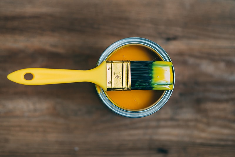 yellow paint in a can and brush