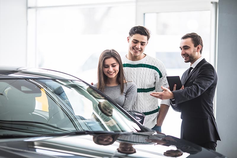 Beautiful young couple choosing a car at the dealership