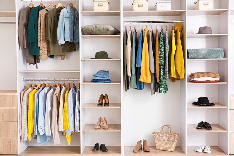 Big wardrobe with clothes in dressing room