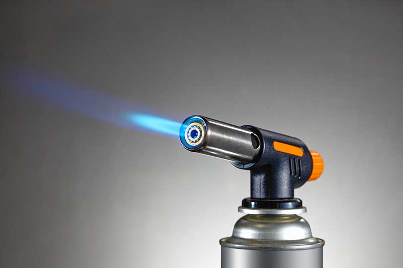 Blowtorch with flame on grey background