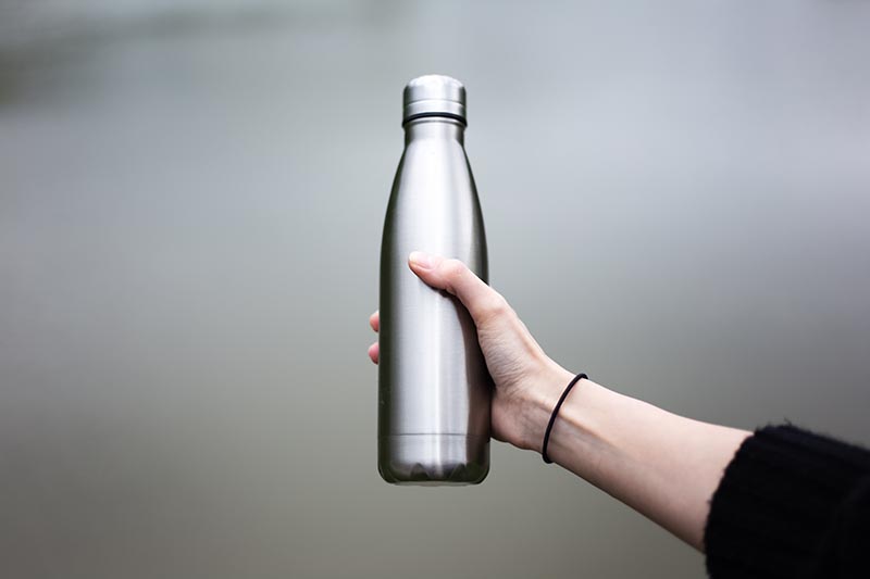 Close-up of steel eco thermo water bottle in female hand