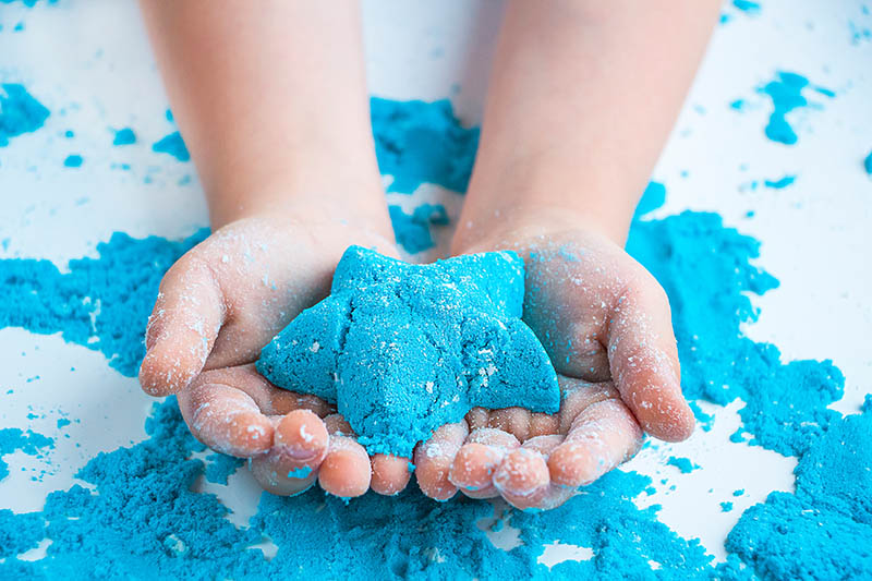 Kinetic sand on a childs hand