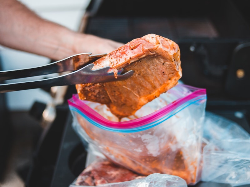 Man putting steak into Zip lock bag