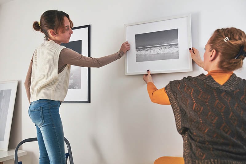 Mother and daughter hanging pictures and photos at home