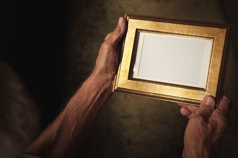 Old man holding and looking at photo frame