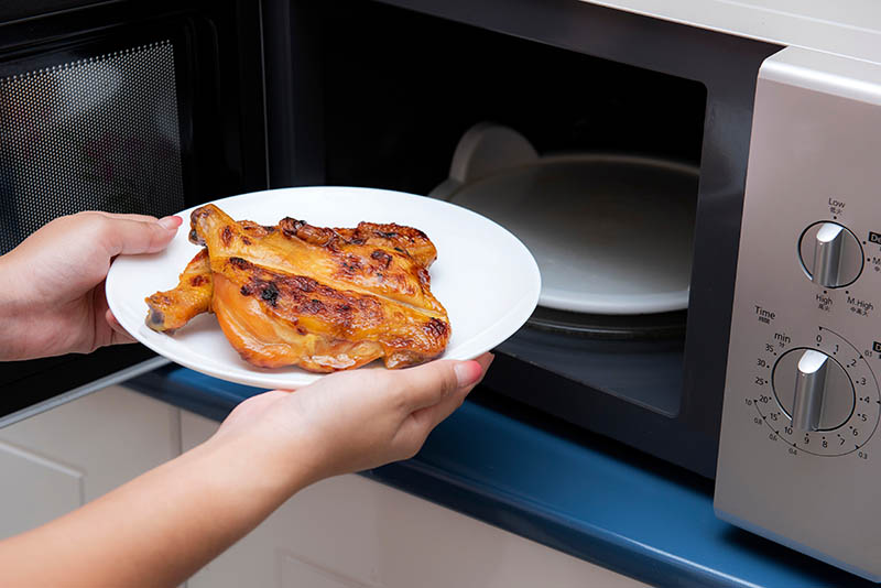 Women hand holding food in a microwave oven