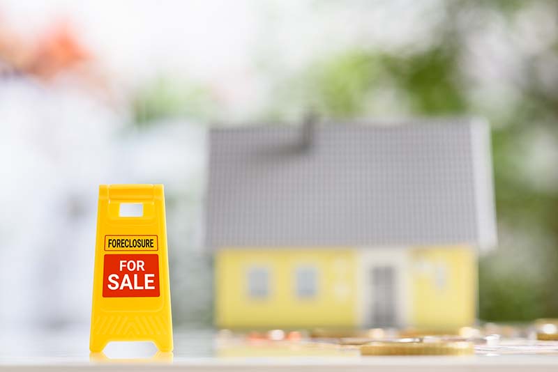 yellow warning or sign board with the words foreclosure for sale
