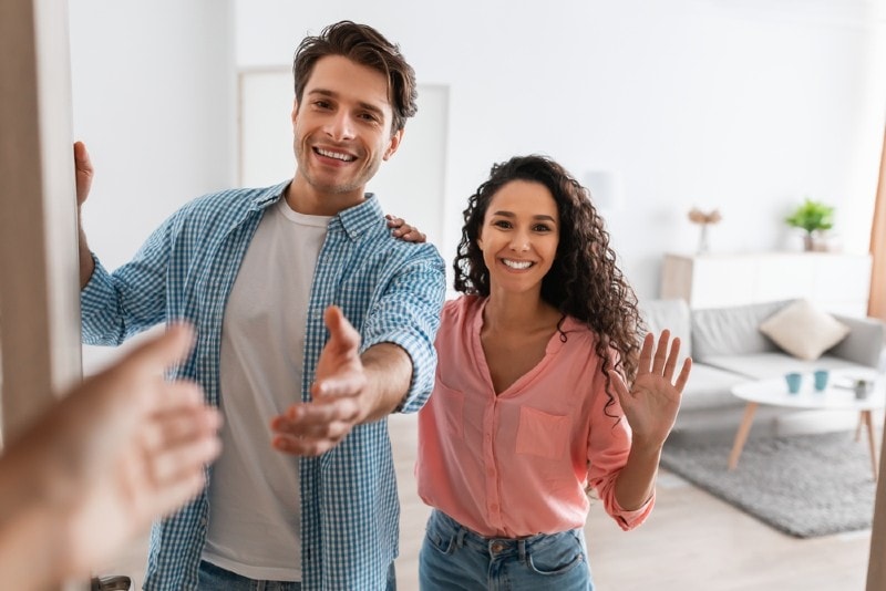 a cheerful couple welcoming guests to an open house