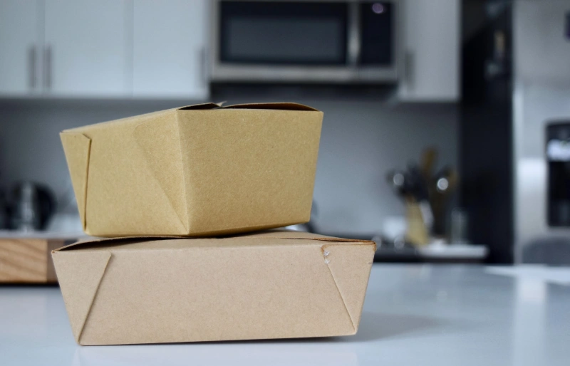 cardboard takeout boxes in a kitchen with a microwave