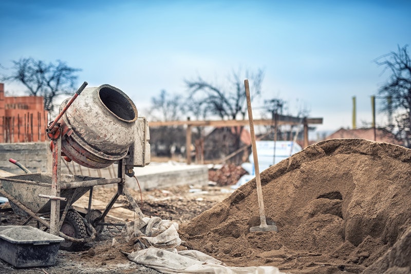 cement mixer machine, tools and sand at construction site